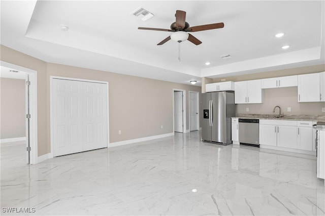 kitchen featuring a raised ceiling, white cabinetry, sink, and stainless steel appliances