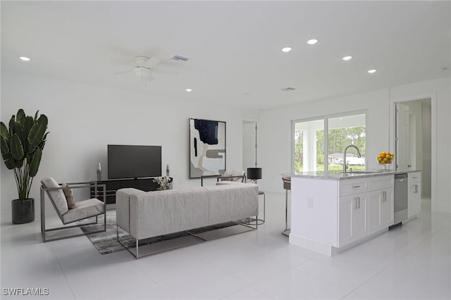 tiled living room with ceiling fan and sink