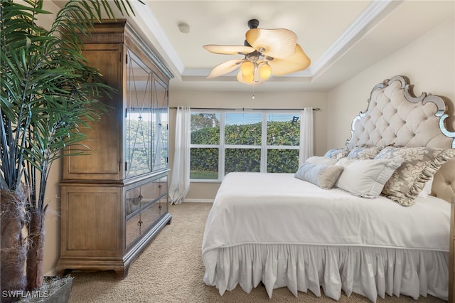 bedroom with ceiling fan, ornamental molding, light carpet, and a tray ceiling