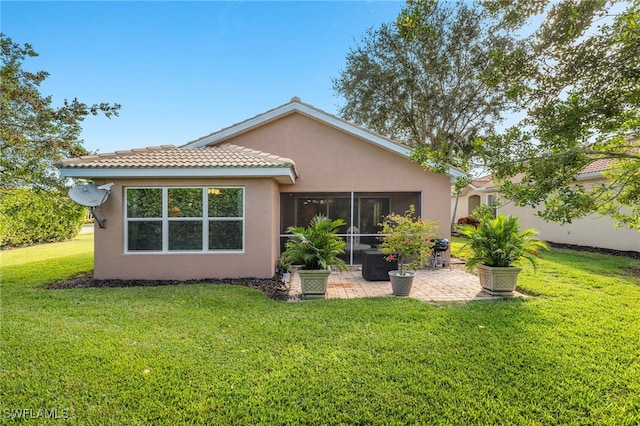 back of property with a lawn, a patio area, and a sunroom