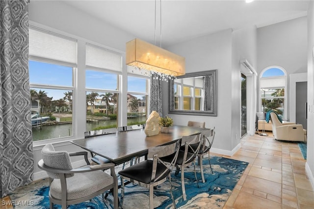 dining space with a wealth of natural light, light tile patterned floors, and a water view