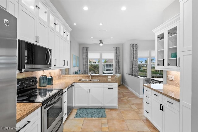 kitchen with decorative backsplash, kitchen peninsula, white cabinets, and stainless steel appliances