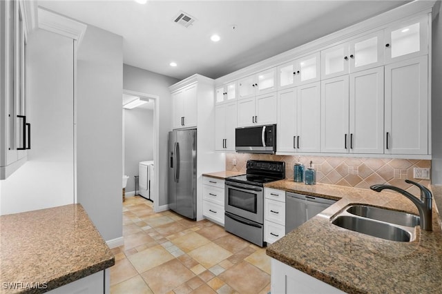 kitchen with sink, white cabinets, washer and dryer, and stainless steel appliances