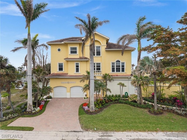 mediterranean / spanish home featuring a garage and a front yard