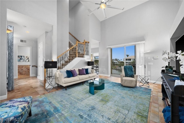 tiled living room with ceiling fan and high vaulted ceiling