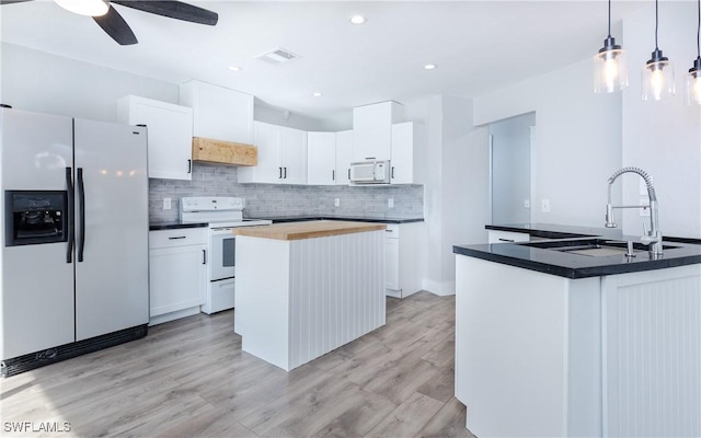 kitchen featuring white appliances, white cabinetry, a kitchen island with sink, and ceiling fan