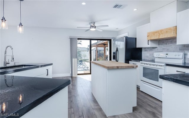 kitchen with white electric range, hanging light fixtures, a kitchen island, white cabinetry, and stainless steel fridge with ice dispenser