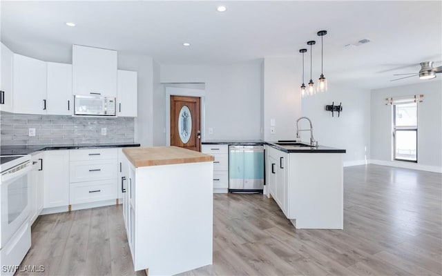 kitchen with white cabinetry, dishwasher, a kitchen island, and hanging light fixtures