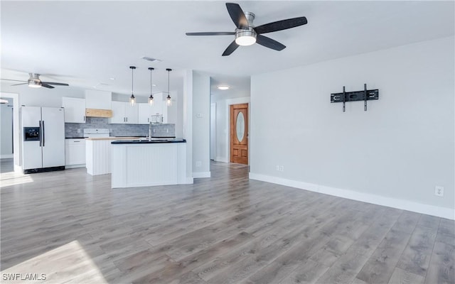 kitchen featuring decorative backsplash, white appliances, sink, white cabinets, and hanging light fixtures