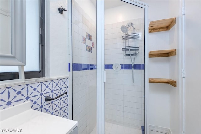 bathroom with decorative backsplash, a shower with door, and vanity