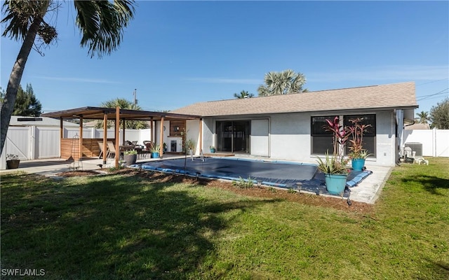 rear view of house with a covered pool, a yard, and a patio area