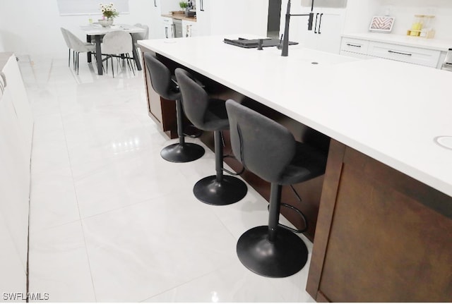 kitchen with a kitchen breakfast bar, white cabinetry, and sink