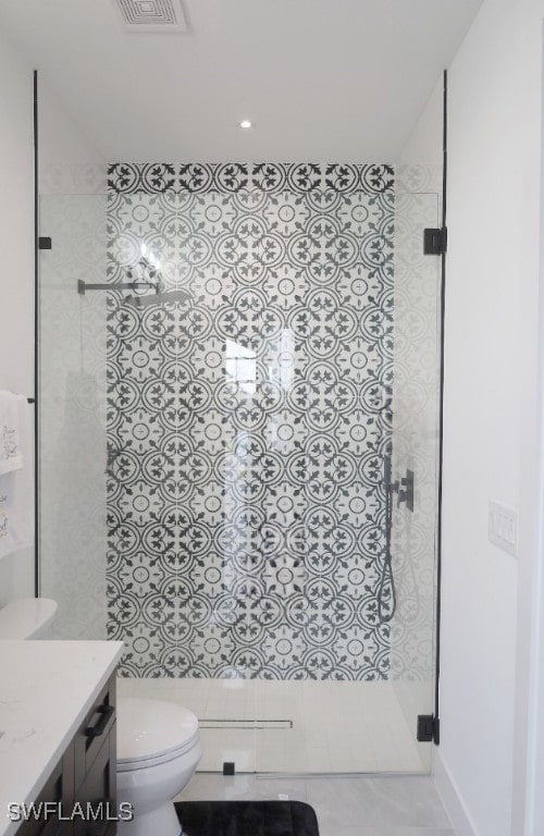 bathroom with tile patterned floors, vanity, a shower with shower door, and toilet