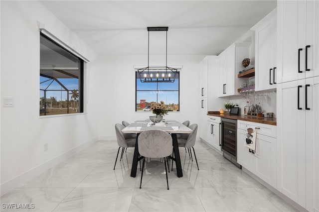 dining space featuring a wealth of natural light, bar area, a notable chandelier, and beverage cooler