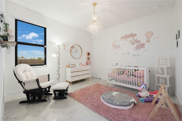 bedroom featuring baseboards, a crib, and a chandelier