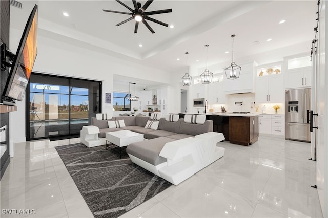 living room featuring a high ceiling, recessed lighting, and ceiling fan with notable chandelier