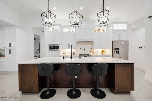 kitchen featuring a sink, a spacious island, appliances with stainless steel finishes, light countertops, and glass insert cabinets