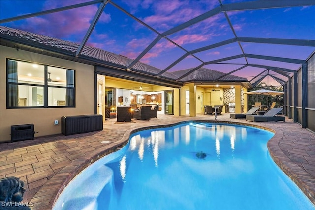 pool at dusk featuring outdoor lounge area, ceiling fan, a patio, and glass enclosure