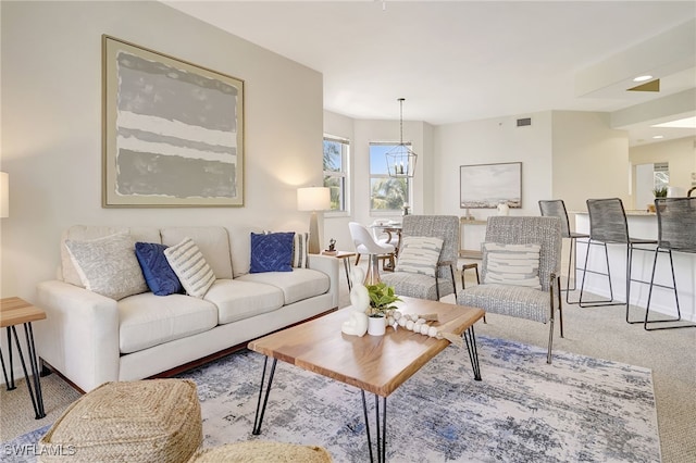 carpeted living room featuring a chandelier