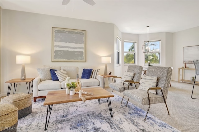 carpeted living room featuring ceiling fan with notable chandelier