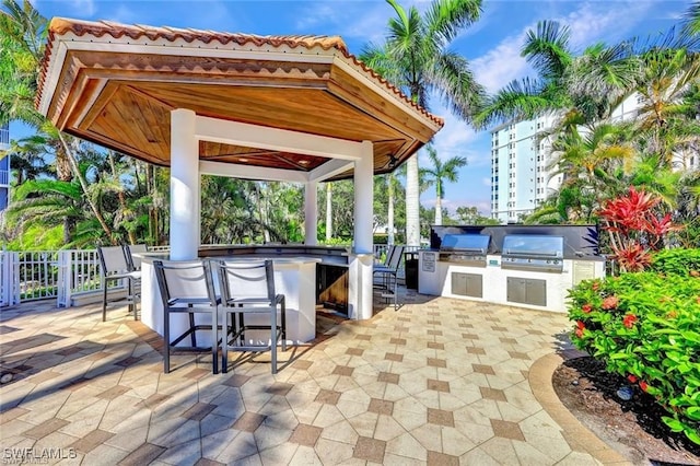 view of patio with a gazebo, exterior kitchen, a grill, and a bar