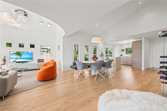 dining room with a towering ceiling and light wood-type flooring