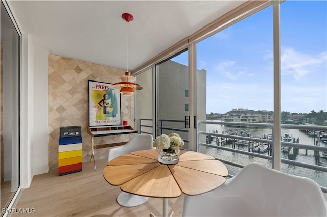 dining room with light wood-type flooring, a wall of windows, and a water view