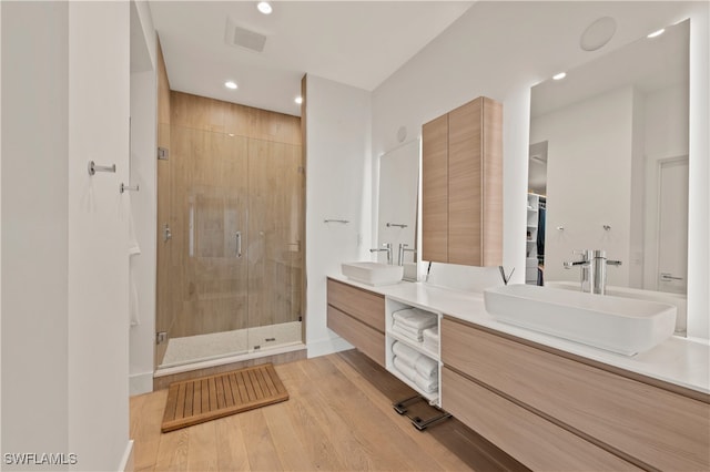 bathroom with vanity, a shower with shower door, and wood-type flooring