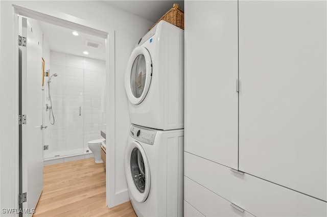 laundry room with stacked washing maching and dryer and light wood-type flooring