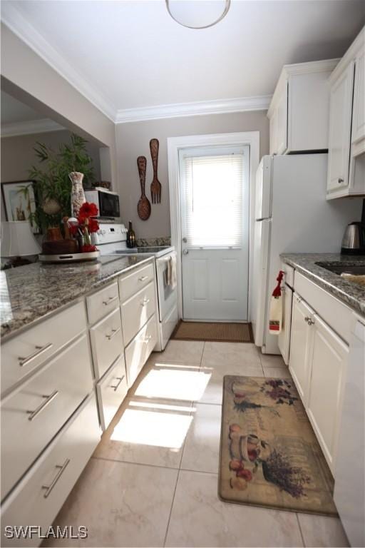 kitchen with white cabinetry, crown molding, dark stone counters, and white appliances