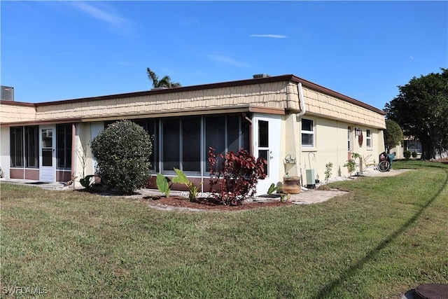 rear view of house featuring a yard and a sunroom