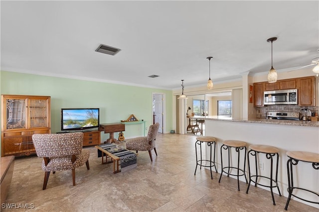 kitchen with crown molding, hanging light fixtures, appliances with stainless steel finishes, light stone countertops, and decorative backsplash