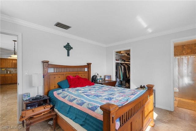 bedroom featuring crown molding, a walk in closet, ensuite bath, and a closet