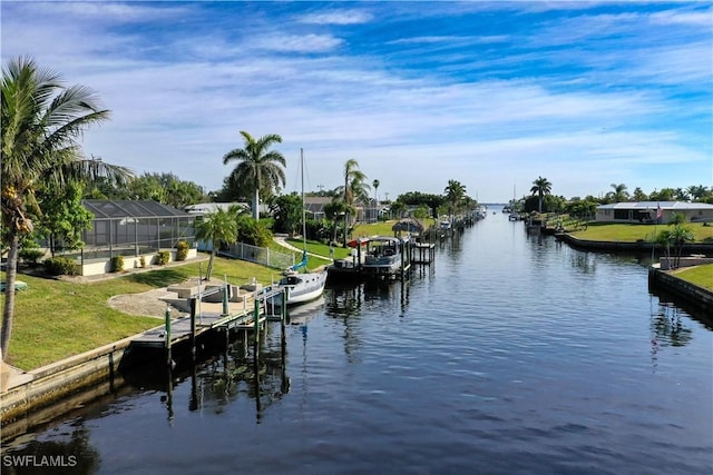 view of dock with a water view, glass enclosure, and a lawn