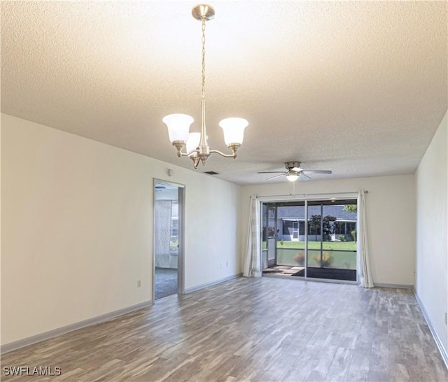 spare room with wood-type flooring, ceiling fan with notable chandelier, and a textured ceiling