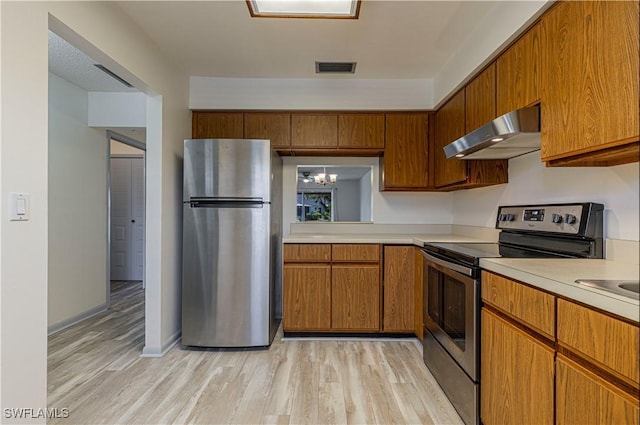 kitchen featuring a notable chandelier, light wood-type flooring, range hood, and appliances with stainless steel finishes