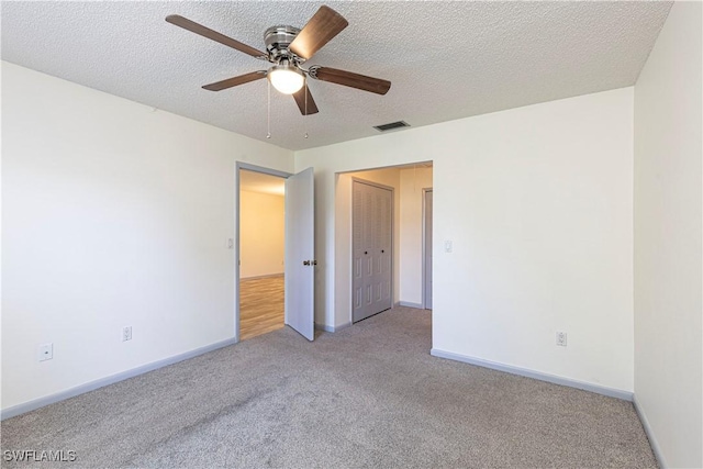 spare room featuring light carpet, a textured ceiling, and ceiling fan