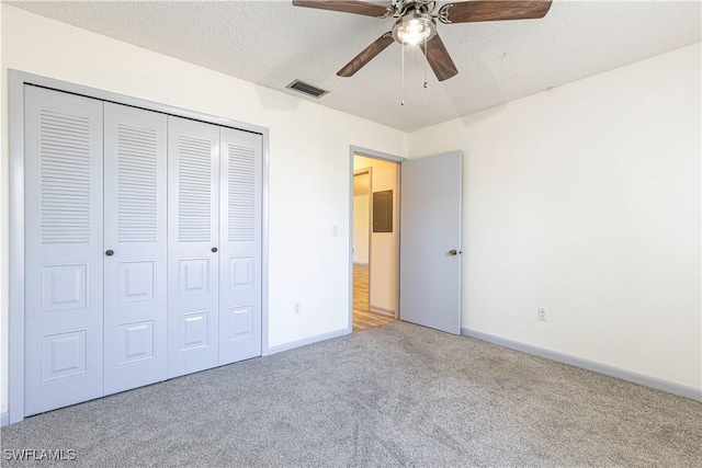 unfurnished bedroom with carpet, ceiling fan, a textured ceiling, and a closet