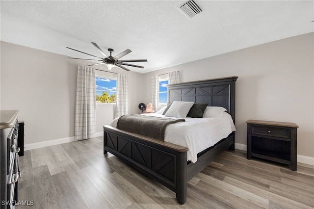 bedroom featuring a textured ceiling, ceiling fan, and light wood-type flooring