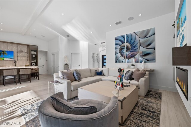 living room with vaulted ceiling with beams and light wood-type flooring