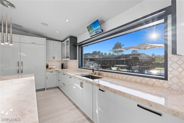 kitchen with white cabinets, light tile patterned floors, sink, and vaulted ceiling