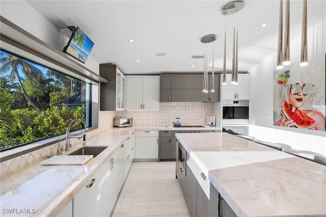 kitchen featuring backsplash, sink, light tile patterned floors, decorative light fixtures, and gray cabinets