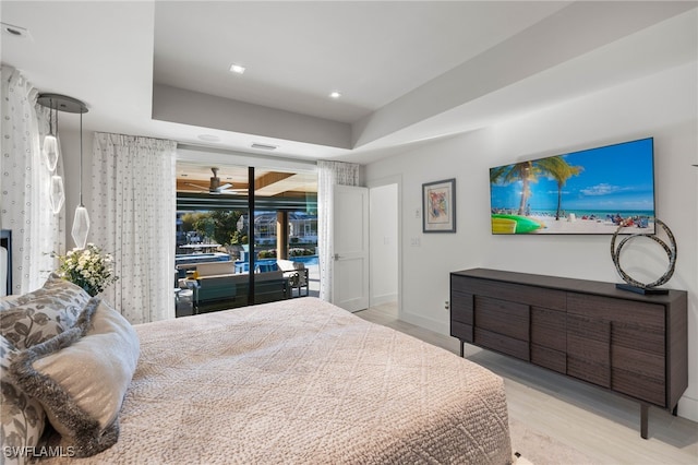 bedroom featuring a raised ceiling, access to exterior, and light wood-type flooring