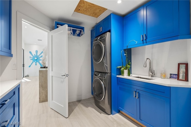 clothes washing area featuring cabinets, stacked washer / dryer, and sink