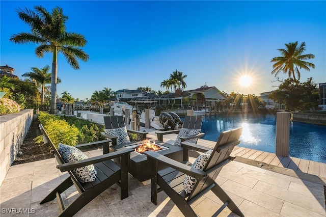 view of patio / terrace with a boat dock, a water view, and a fire pit