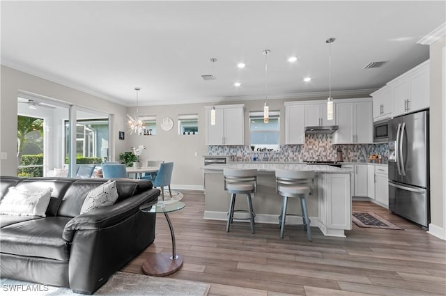 kitchen featuring white cabinets, pendant lighting, a breakfast bar area, a kitchen island, and appliances with stainless steel finishes