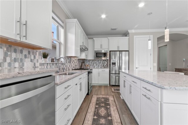 kitchen featuring appliances with stainless steel finishes, tasteful backsplash, pendant lighting, white cabinetry, and a kitchen island