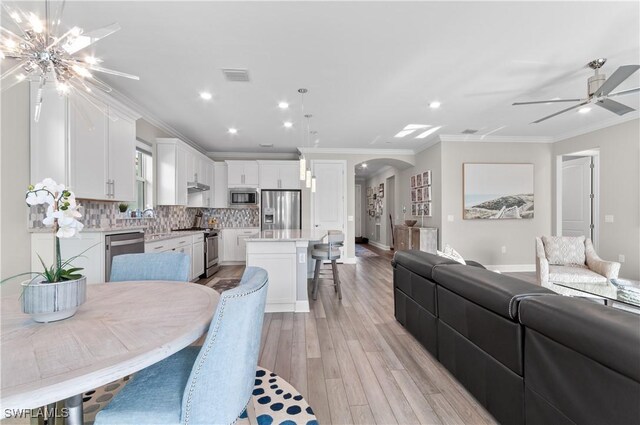 interior space with white cabinetry, a center island, tasteful backsplash, decorative light fixtures, and appliances with stainless steel finishes