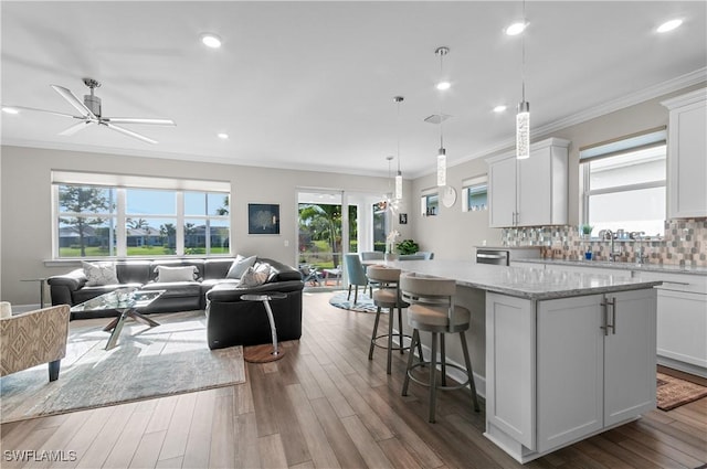 kitchen featuring decorative light fixtures, a center island, light stone counters, and white cabinetry