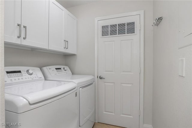 laundry area with washing machine and clothes dryer and cabinets